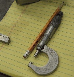 A writing tablet with a pencil and various other tools laid across it.